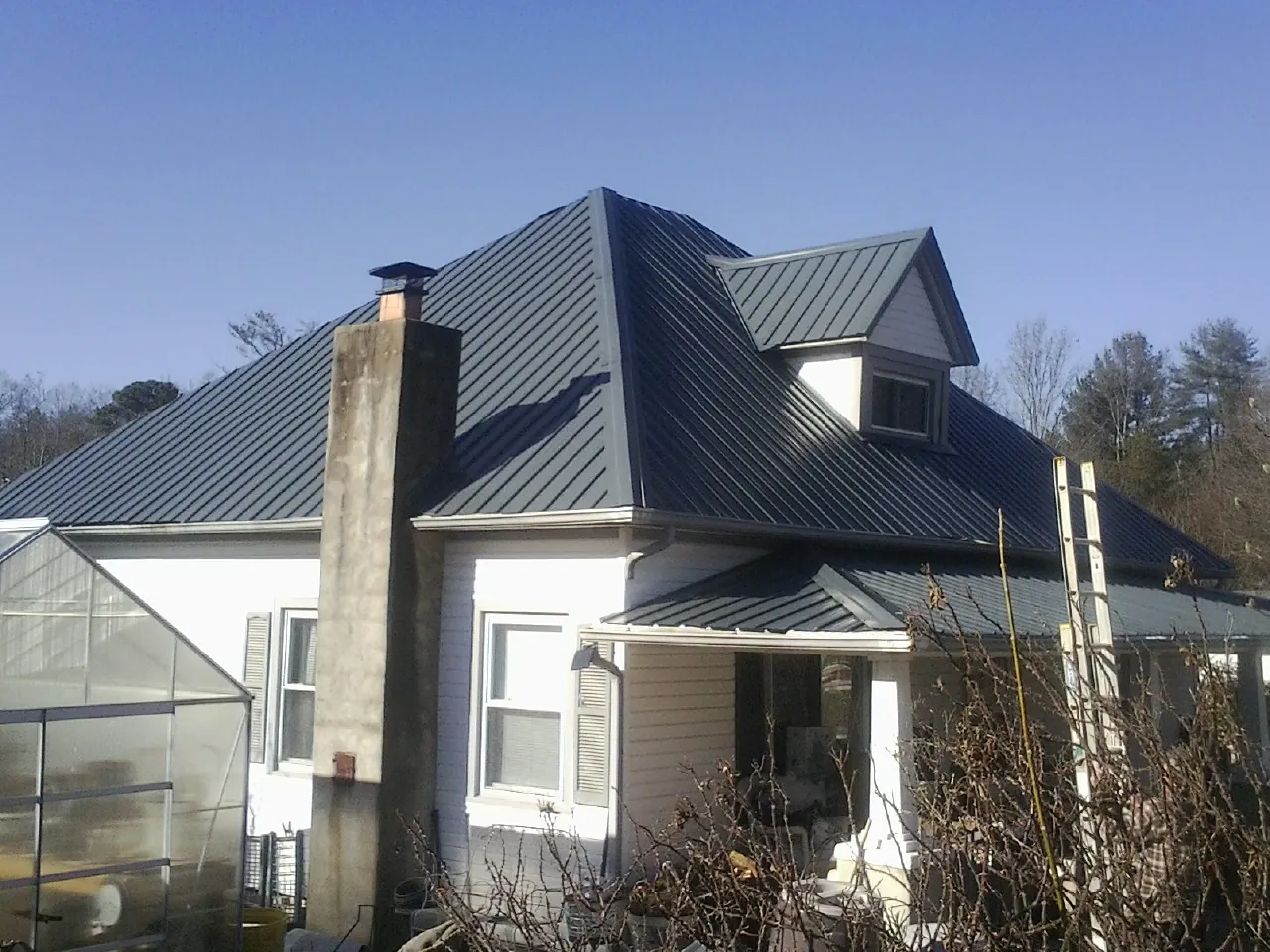 Dark blue standing seam metal roof on a white farmhouse with dormer — Slate & Tile Roof Repair by Roofing Brothers in Visalia