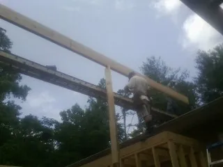 Carpenter setting a ridge beam over a new addition frame — Ice Dam Removal by Roofing Brothers in Visalia