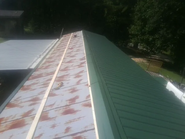 Old rusted panels beside newly installed green metal roofing — Wind Damage Roof Repair by Roofing Brothers in Visalia