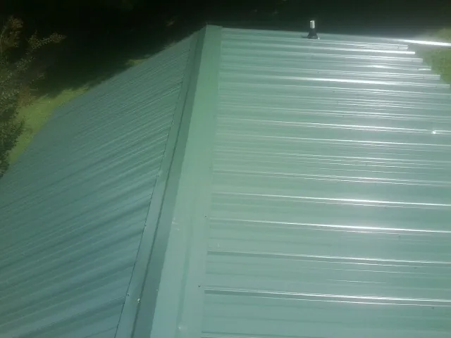 New green metal panels meeting at the ridge of a roof — Flat Roof Repair work by our crew in Visalia