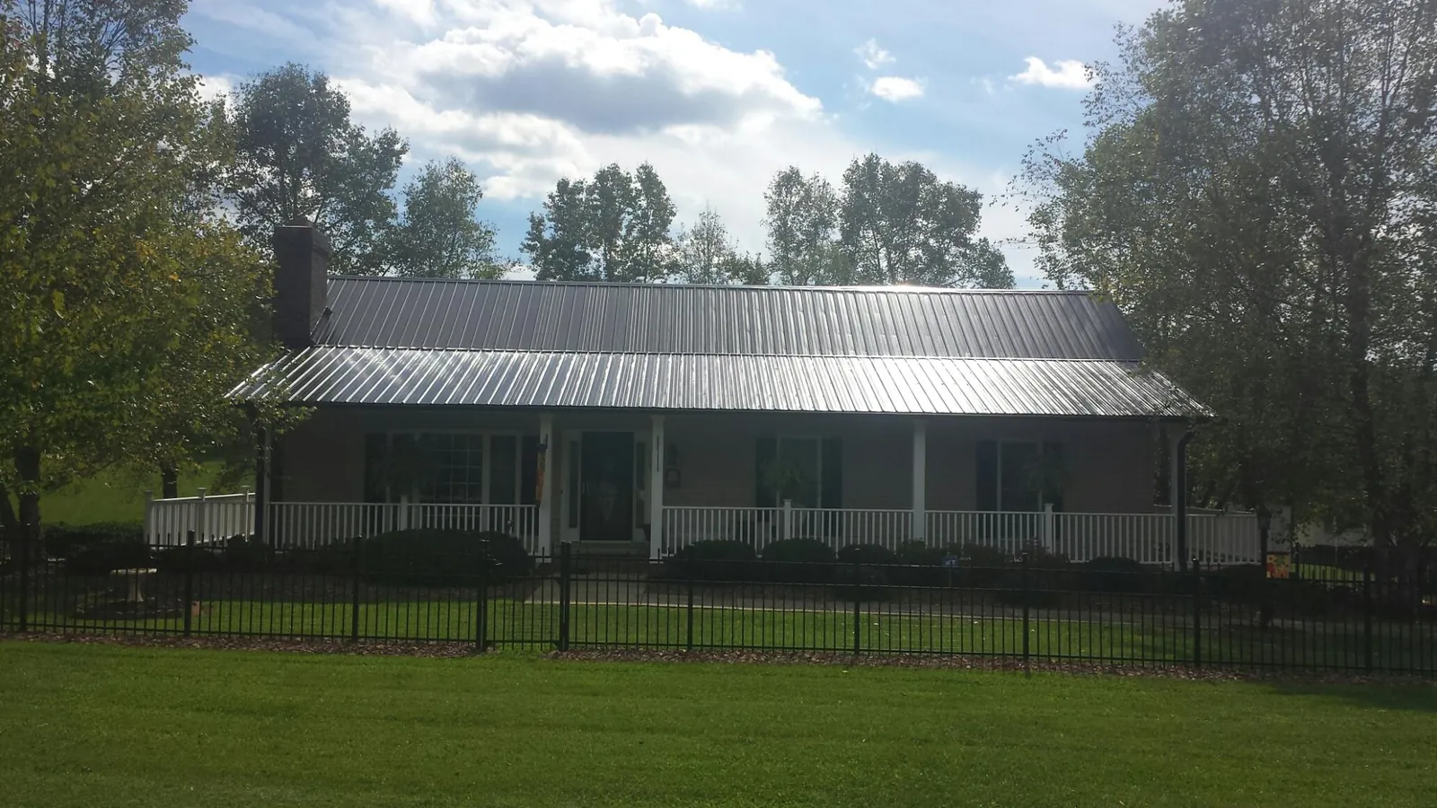 Gray metal roof on a brick ranch with a full width front porch — Gutter Guard Installation work by our crew in Visalia