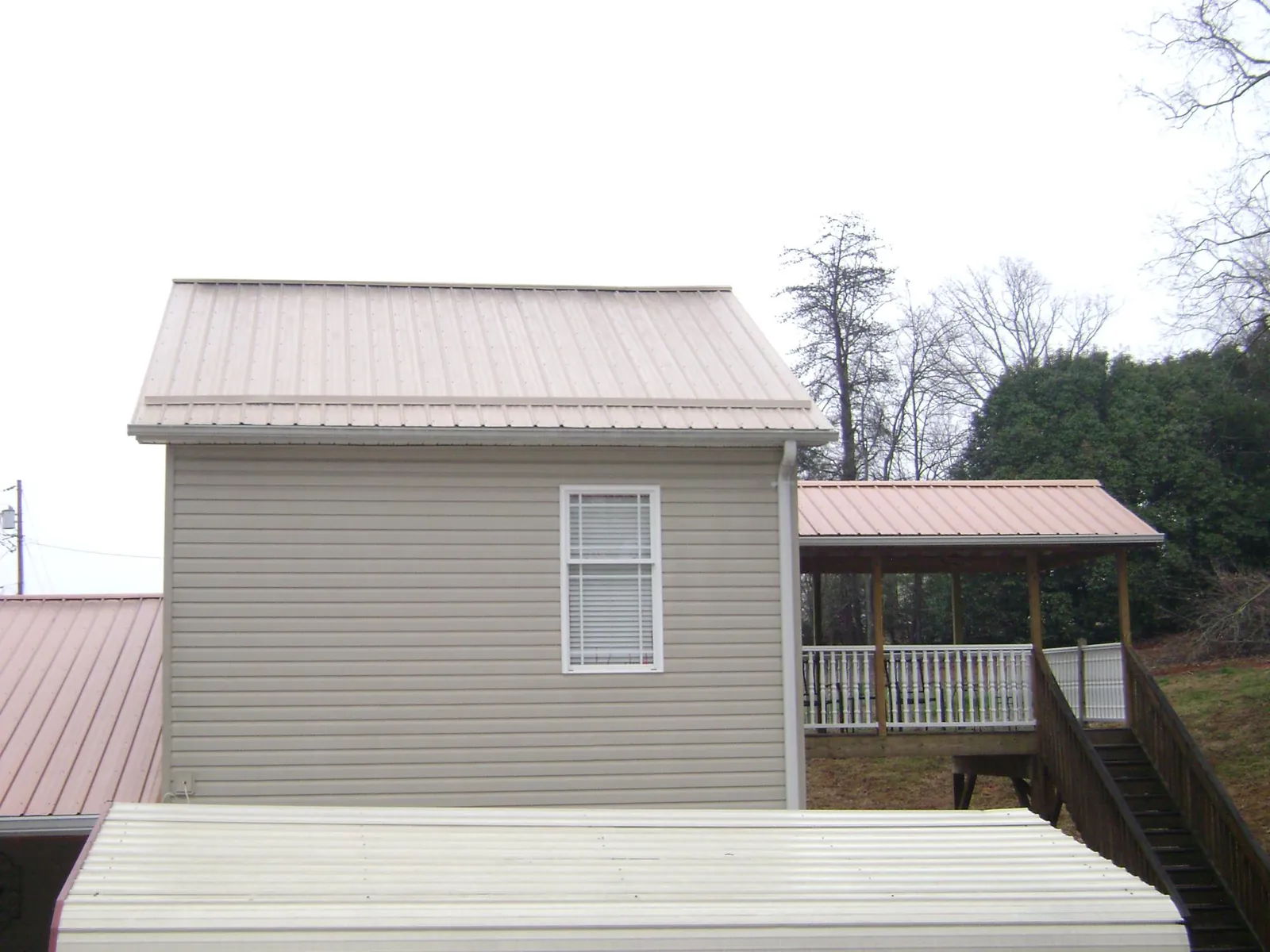 Tan metal roofs on a two story addition and attached porch, from a Roof Replacement job in Visalia