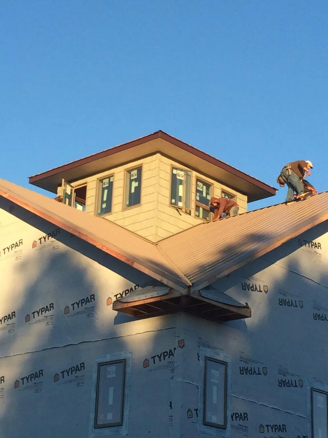 Roofers working around a rooftop cupola on a new metal roof at sunset — Roof Waterproofing in Visalia by Roofing Brothers